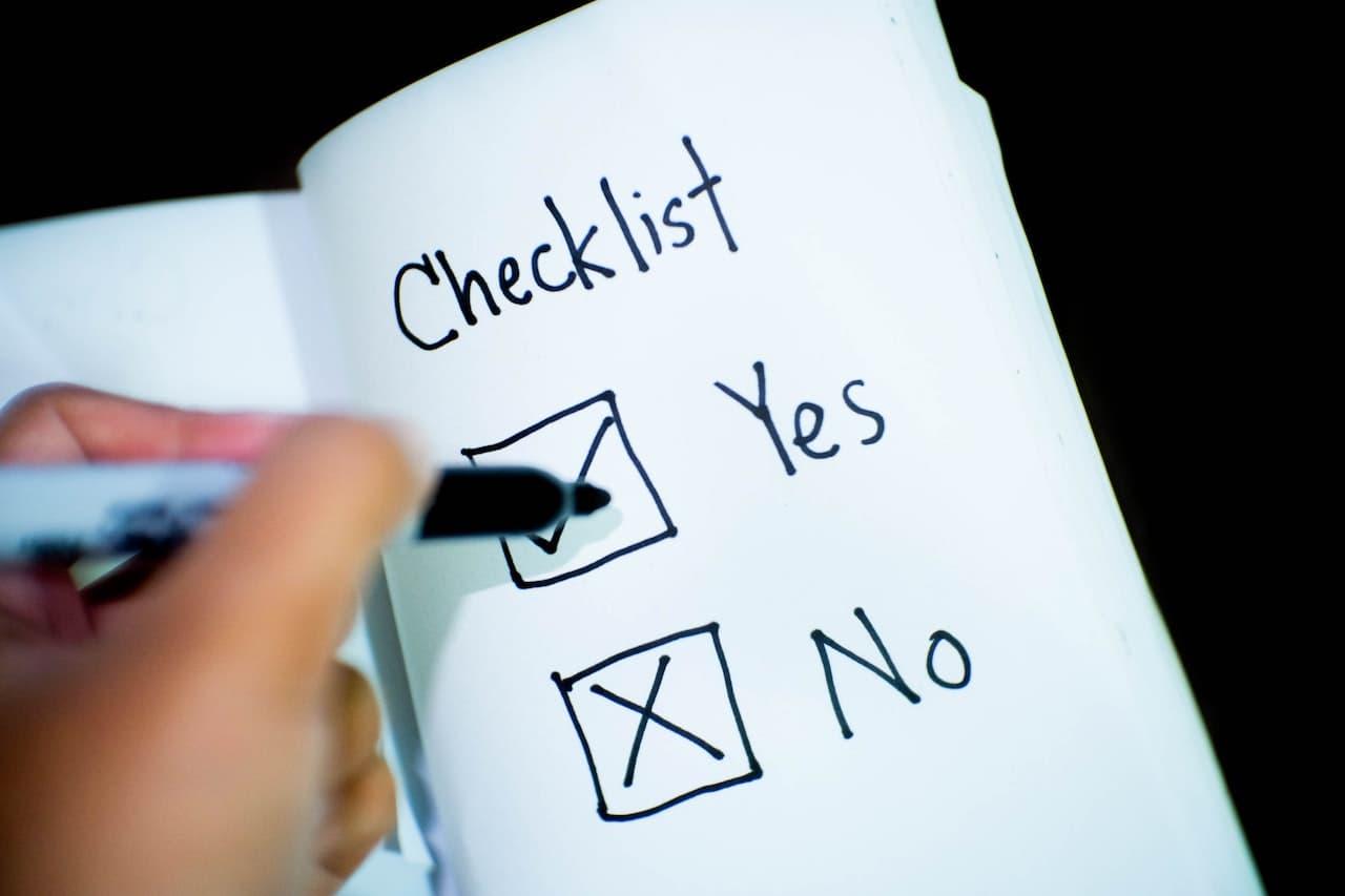 Hand marking the Yes box on a handwritten checklist in a notebook, with the No box crossed out